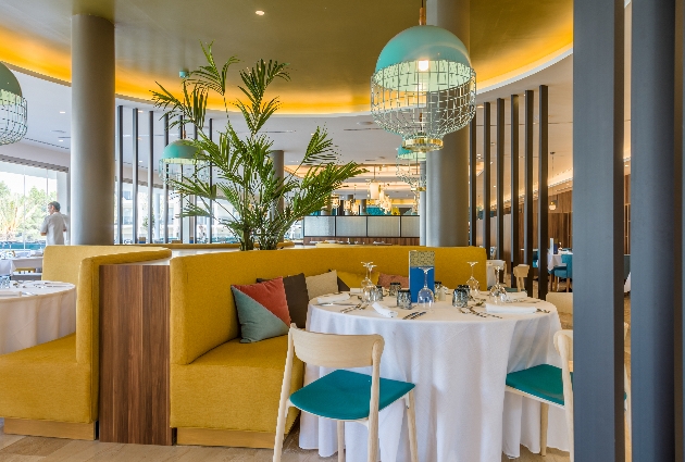 Yellow bench seating surrounds a white-linen dressed round table