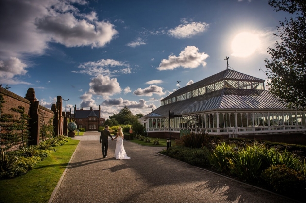 Wedded couple walk past The Isla Gladstone conservatory