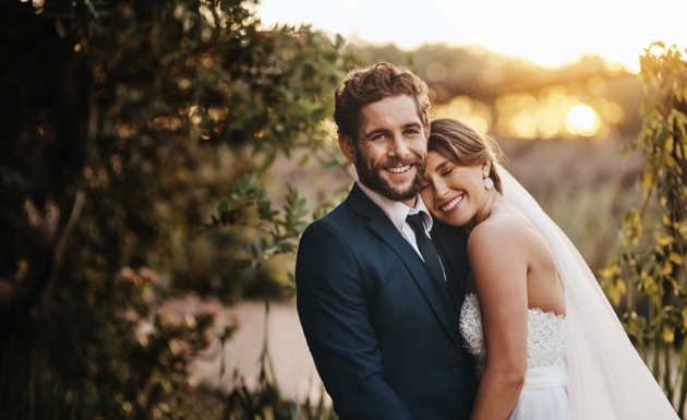 Bride and groom by a lake at sunset