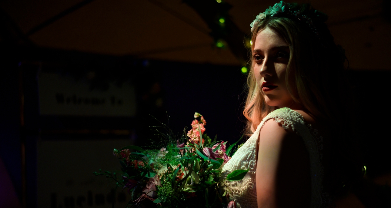 Bride dramatically lit inside a tipi holding a bouquet