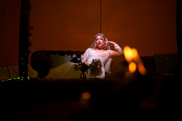 bride reclining on a sofa with a flame in the foreground