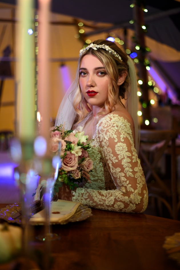 bride wearing lace sleeved dress and hair vine. Candelabra in the foreground