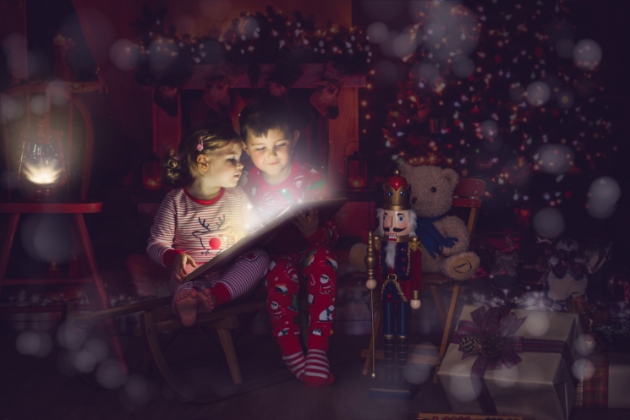 Little boy and girl reading a christmas book in front of the christmas tree