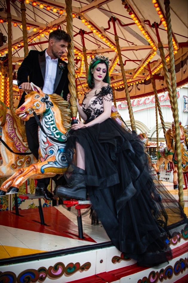 Bride and groom dressed in black on carousel