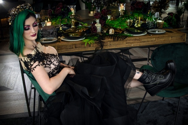 Bride dressed in black sitting at wedding reception table