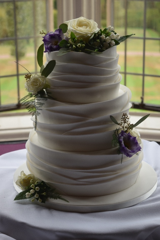 Ruffled icing wedding cake with white and blue flowers
