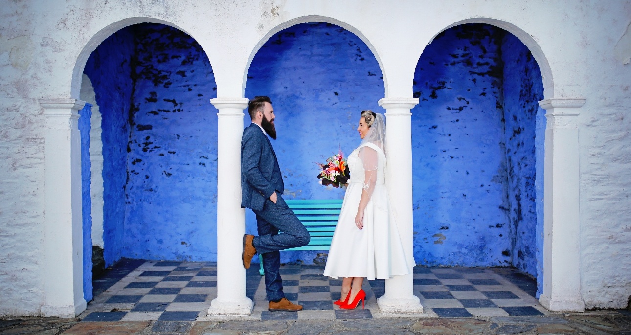 Couple standing beneath arches painted in white and blue in Portmerion