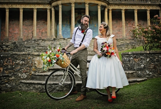 bride and groom in portmerion leaning on a bicycle