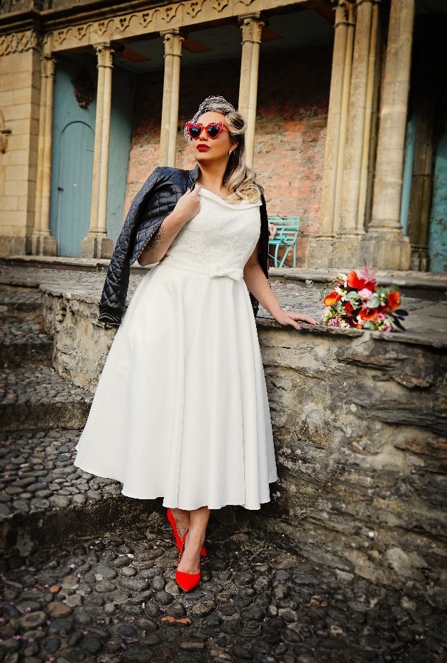 bride wearing tea-length dress, heart-shaped sunglasses, leather jacket and red shoes