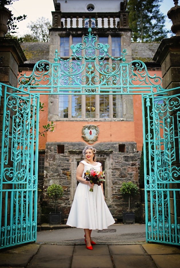 Bride in front of teal green gates in portmerion