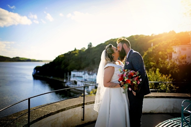 bride and groom kiss in front of the north wales coastline