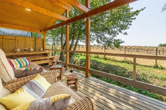 wooden lodge table and chairs on terrace looking out to fields