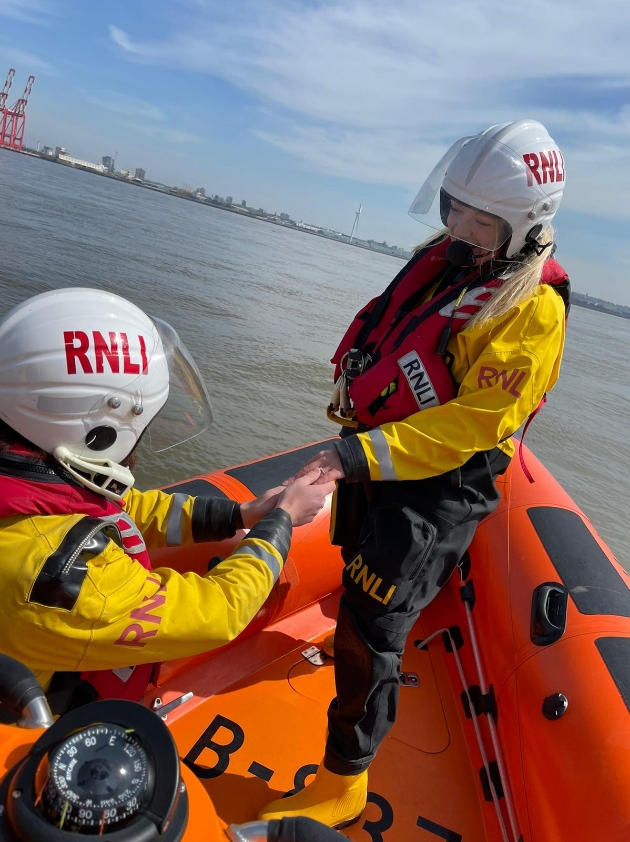 Tom on one knee proposing to Emily in lifeboat