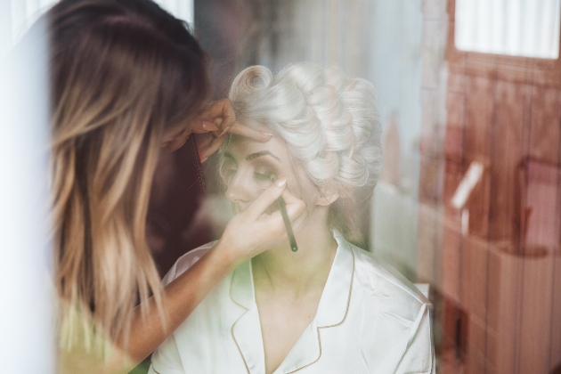 Leader doing a bride's eye makeup. Bride's hair is in rollers