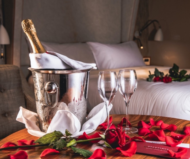 Bottle of Bollinger in an ice bucket with red rose petals scattered all around