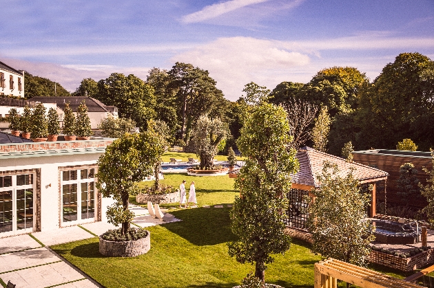 outdoor view of hotel, hot tub, pool and two people in robes walking round the gardens