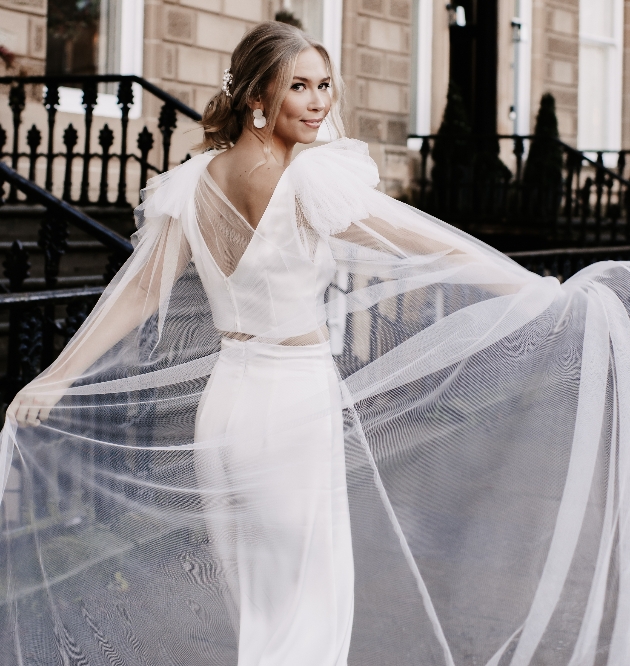 Bride on the street wearing a bridal two piece and veil cape
