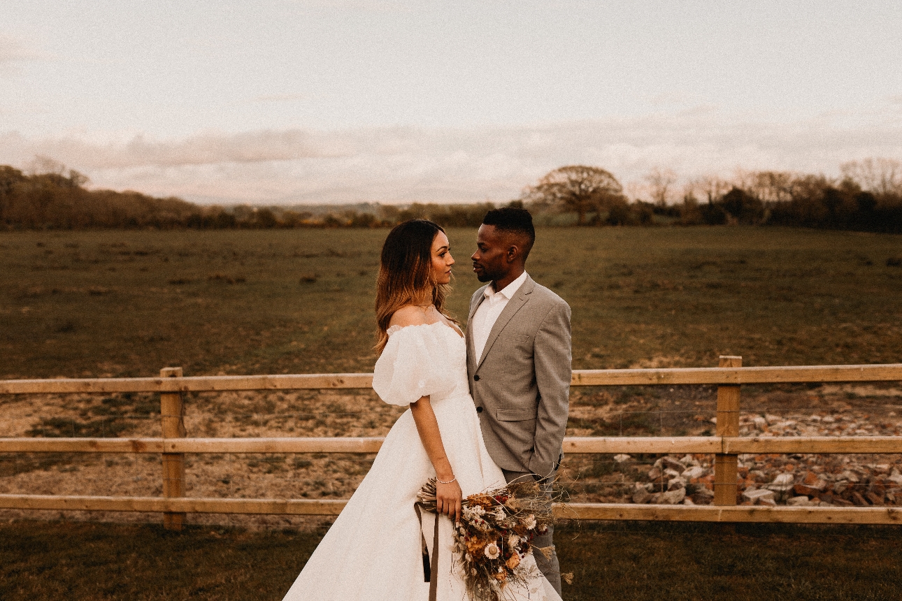 wedding couple standing by a field