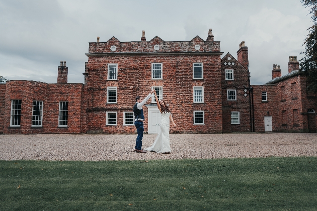 Bride and groom in front of Meols Hall. Groom is spinning bride around. 