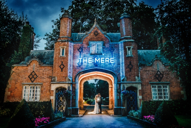 Bride and groom at dusk beneath The Mere gate house