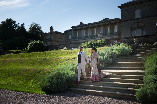 Bride and groom walking hand in hand down the steps at Tatton Park