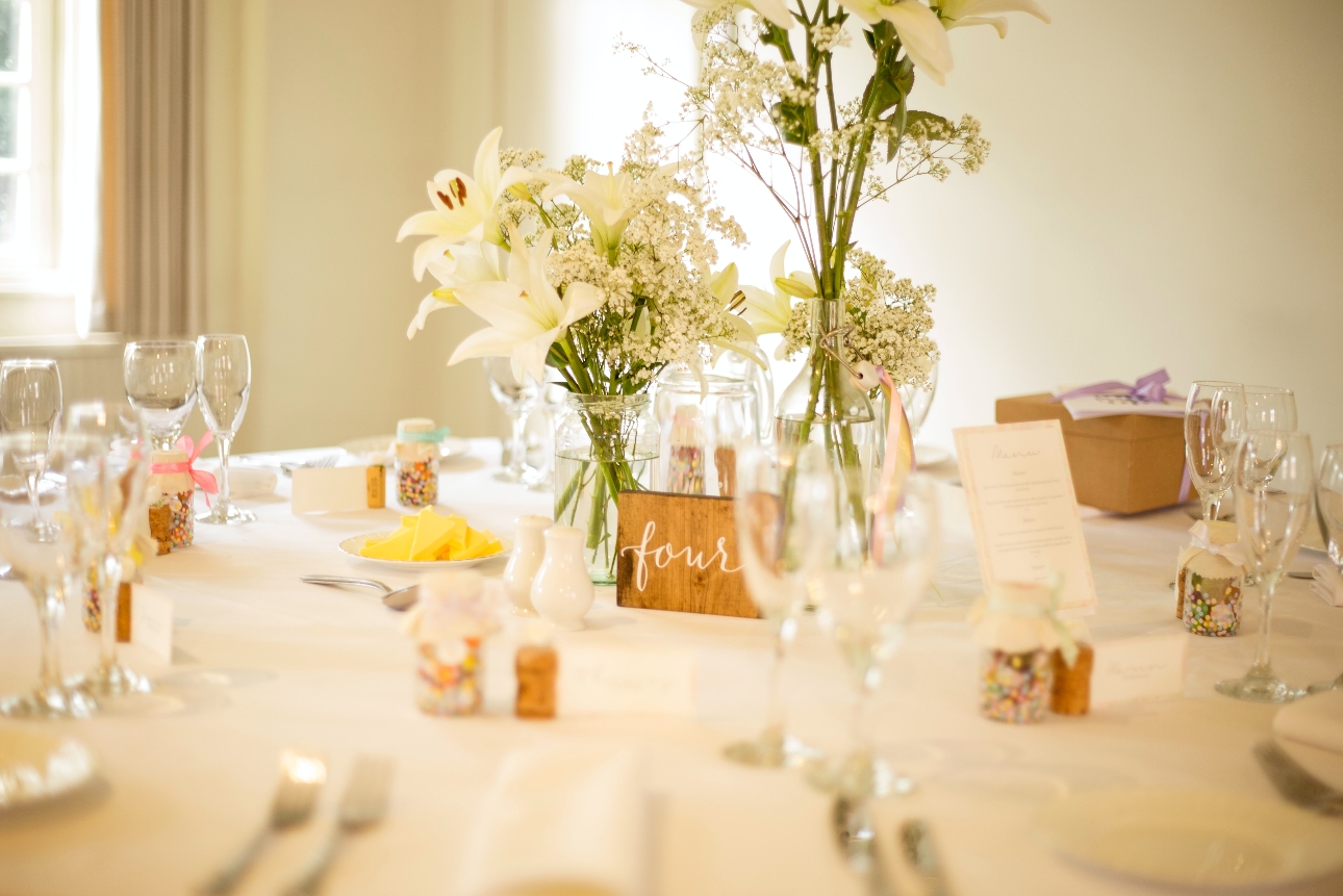 table at a wedding reception set up for a wedding breakfast with plates, glasses, linen and favours