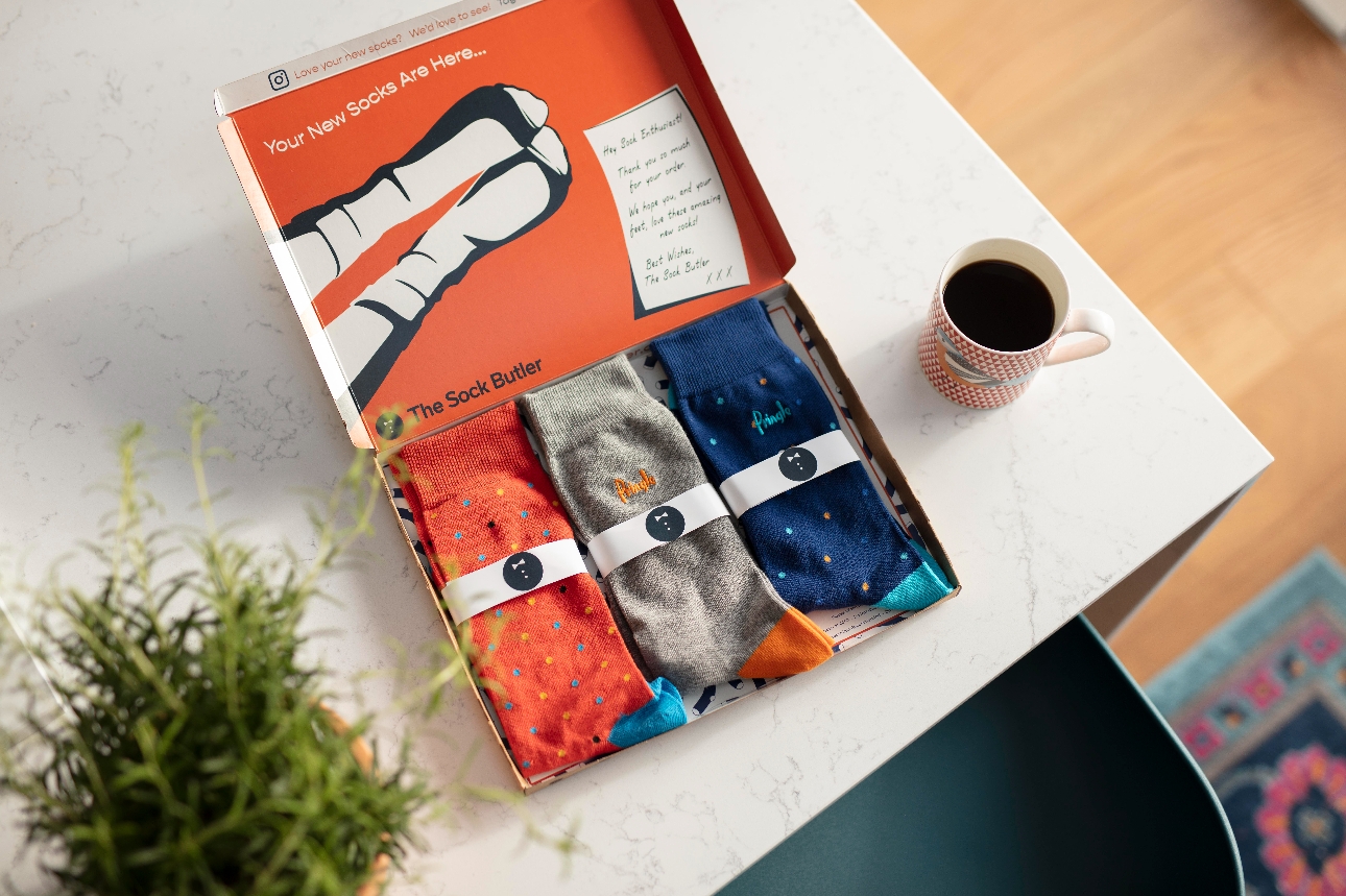 box of three different coloured socks on a table. 