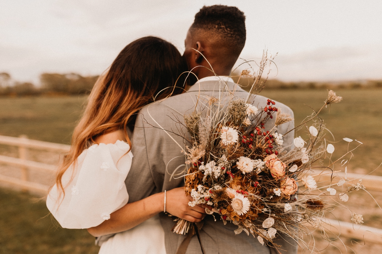 couple in wedding attire looking out to field