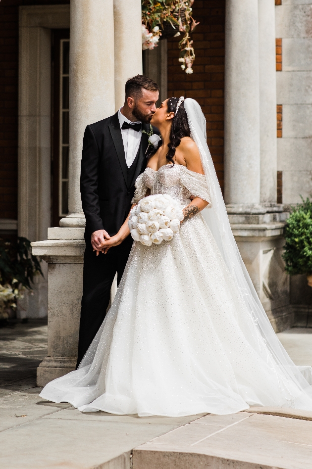 Bride and groom kissing in front of Eaves Hall