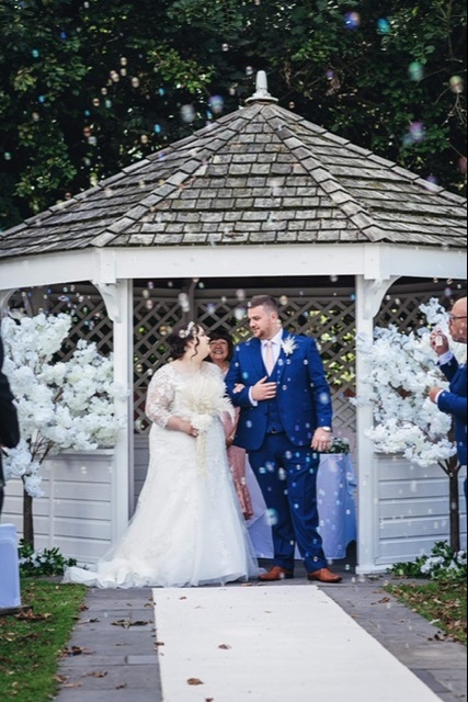 Bride and groom surrounded by confetti as they walk down the aisle