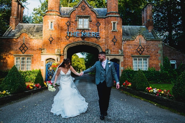 Bride walking hand in hand outside The Mere Golf Resort & Spa