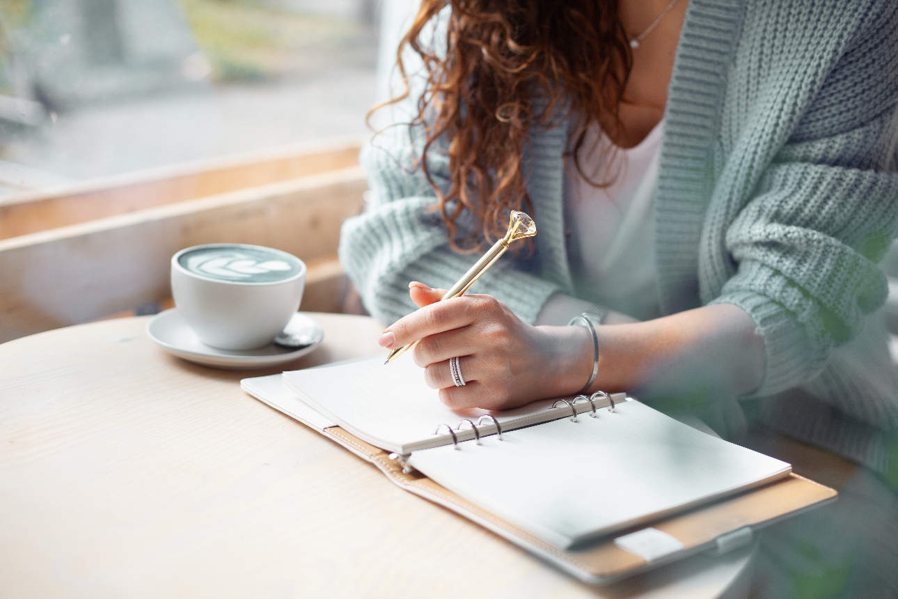 woman in a cardigan with a planner and pen