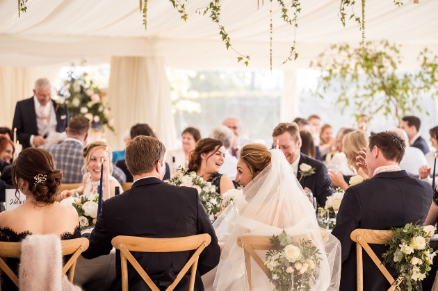 couple sat with their guests at a wedding reception