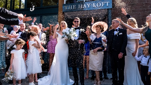 Bride and groom being showered with confetti outside The Hay Loft at Allerton Manor Golf Club