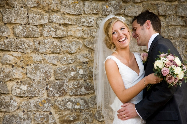 Bride and groom laughing stone wall backdrop