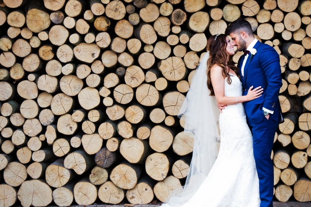 Bride and groom in front of a log pile backdrop