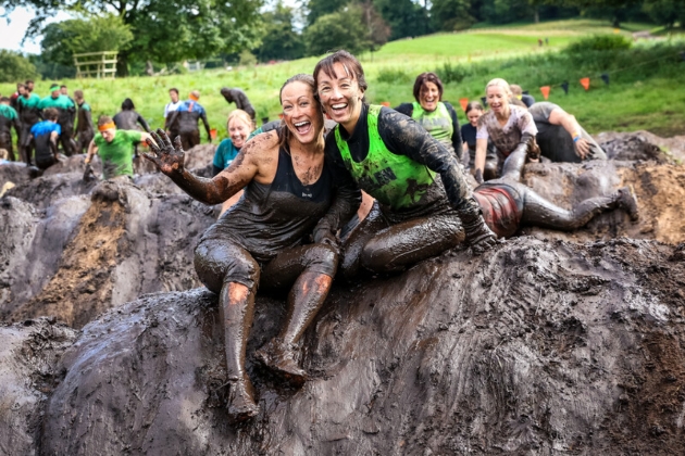 Two friends covered in mud taking part in Tough Mudder