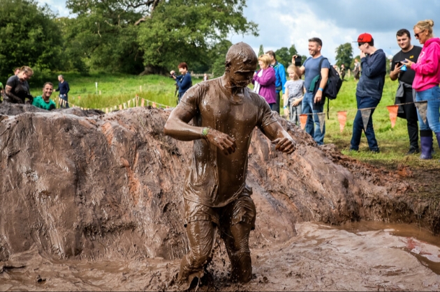 Man covered head to toe in mud competing in Tough Mudder