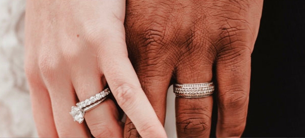 man and woman's hands intertwined both wearing wedding rings and bands