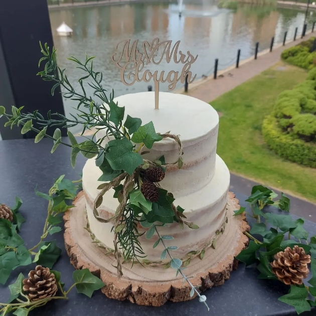 rustic semi-naked wedding cake decorated with pine cones and ivy