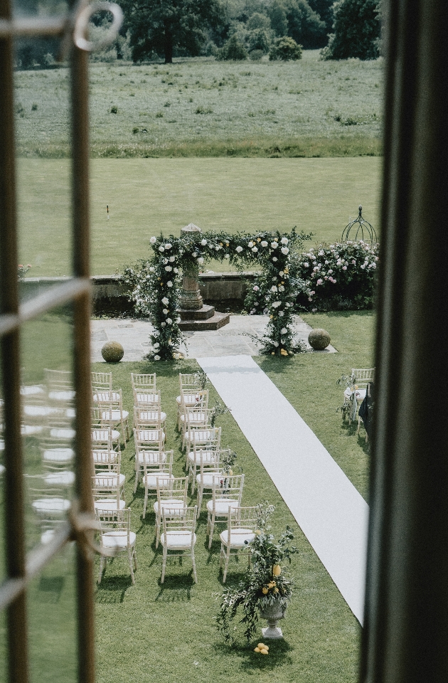 Al fresco ceremony area seen from an upper window. While flower arch, pew ends and urns