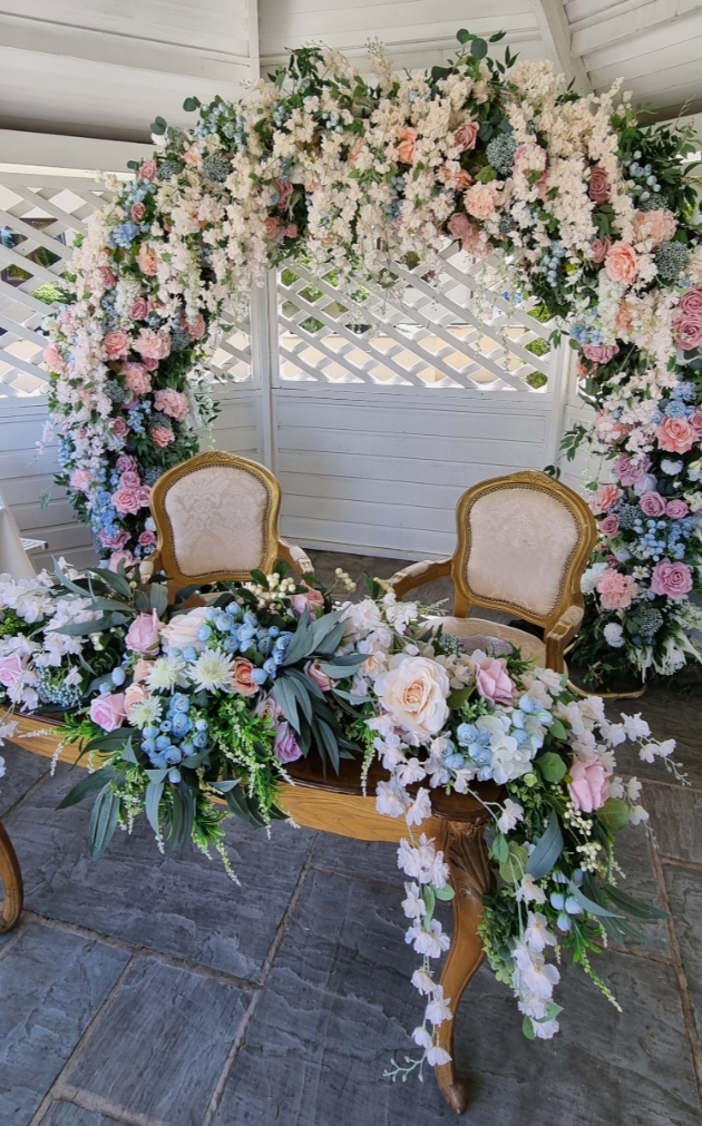 Pink, blue and white ceremony arch and registration table florals