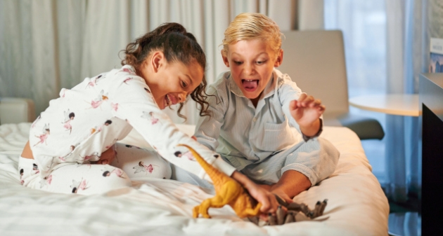 Kids on a bed playing dinosaurs