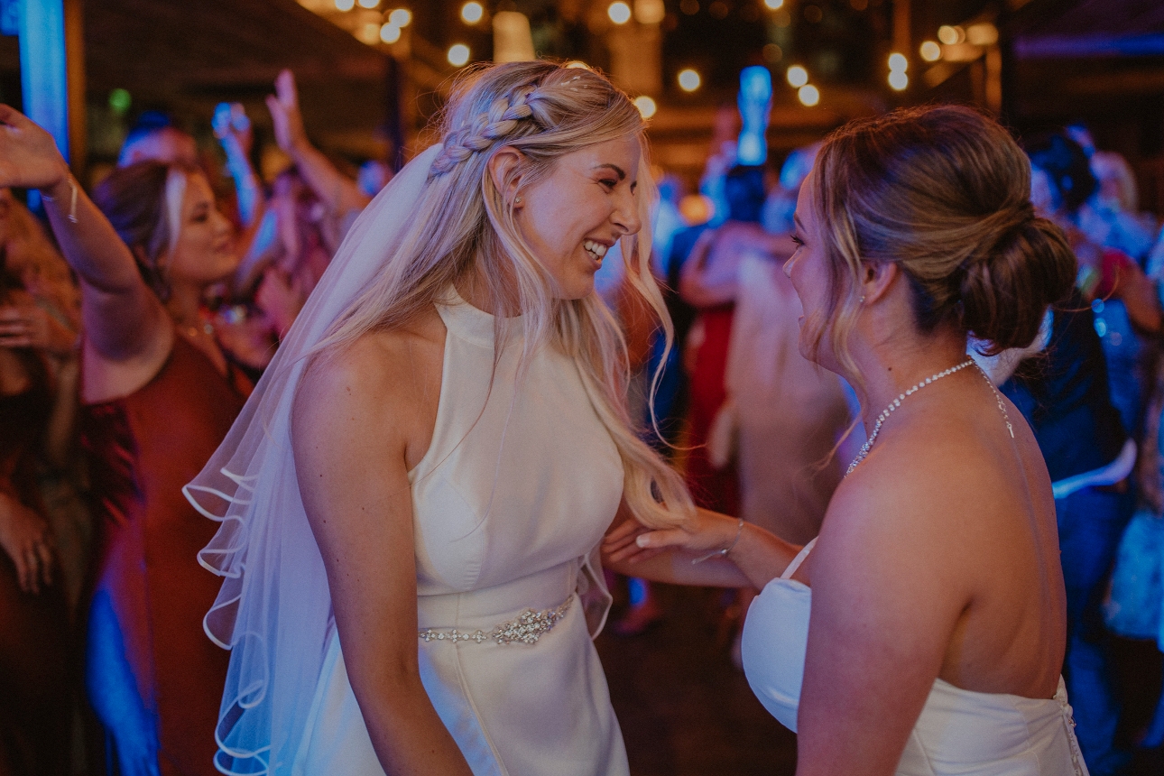 two brides dancing first dance surrounded by their guests