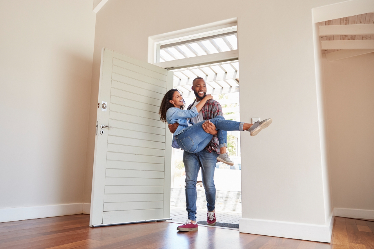 man carrying woman over threshold of new house