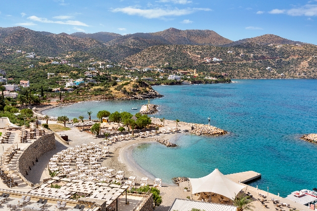 A beach with sun loungers on with mountains in the background