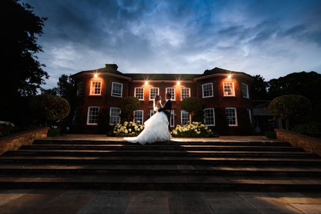 Delamere Manor at dusk with bride and groom in front of it.