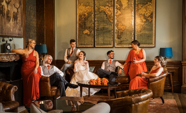 informal yet staged shot of bridal party in burnt orange colour palette in stately home venue with leather sofas