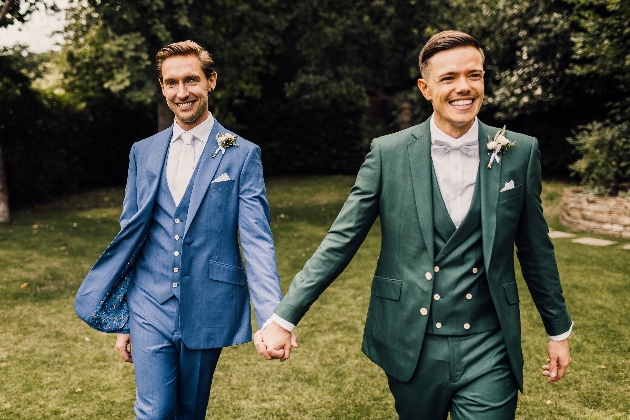 two grooms hand in hand in their King & Allen suits
