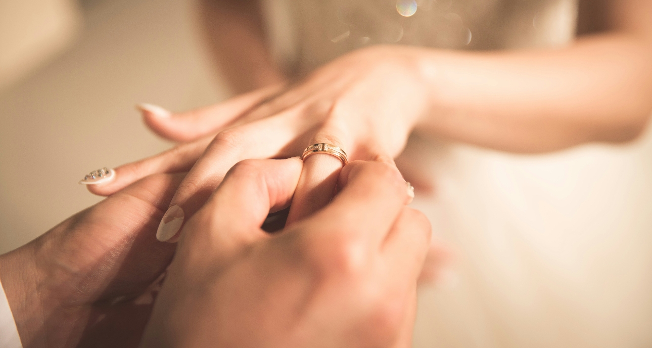 groom putting wedding ring on bride's finger